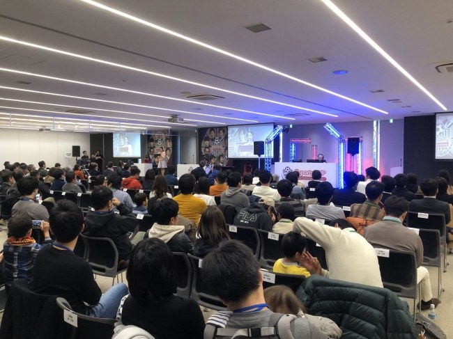 NTT西日本グループの社内eスポーツ大会の決勝会場。家族や職場の応援者が客席から観戦している